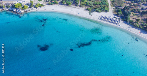 Crystal clear and turquoise sea and white sandy beach surrounded with trees. Aerial view 