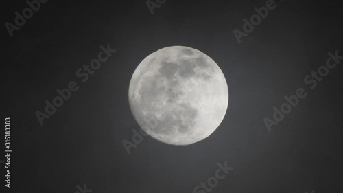 Full moon on dark cloudy night. Clouds passing by the moon, real time shot.