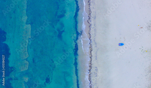 Blue boat on the sandy beach by the turquoise clear sea 