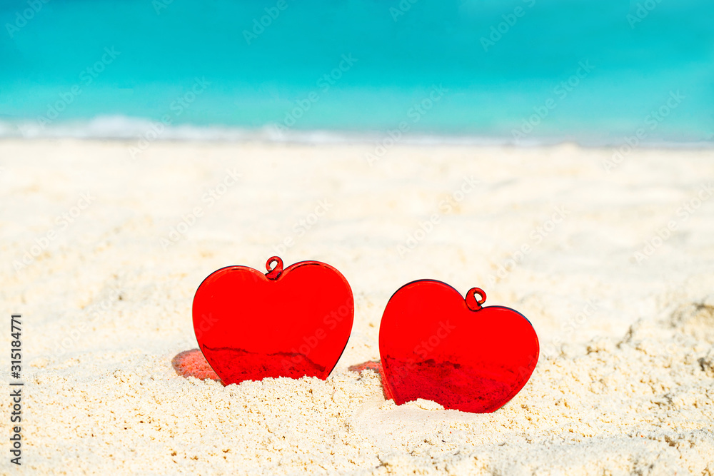 Fototapeta premium Red Heart shape on white yellow sand beach. Love concept for Valentine Day or summer vacation.