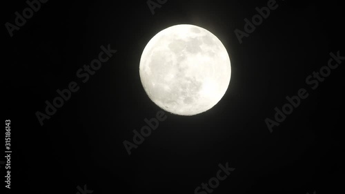 Full moon on dark cloudy night. Clouds passing by the moon, real time shot.