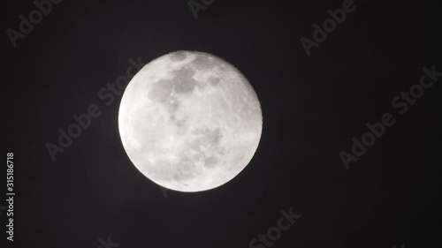 Full moon on dark cloudy night. Clouds passing by the moon, real time shot.