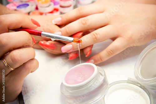 Master applies gel polish on nails in manicure salon