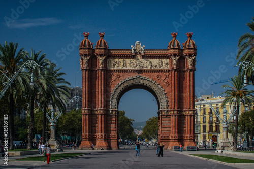 Arc de triomphe or arch of triumph in Barcelona, Spain in a clear sunny day with only a few tourists lingering by. Frontal shot of Arc de Triomphe in Barcelona.