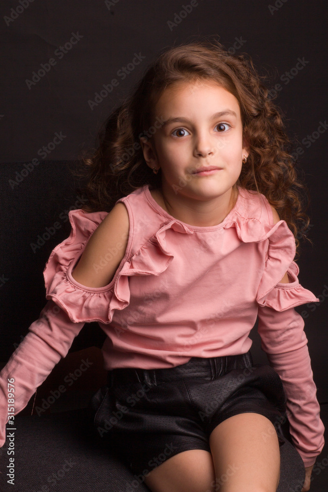 Studio portrait of a little girl with long curly hair, in a pink skirt and black shorts, Studio portrait of a little girl with long curly hair, in a pink skirt and black shorts,