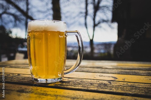 Mug of beer in a mountain hut like ambient. Jug of beer with nobody walking past in the background. Concept of well deserved beer on the top of the hill. photo