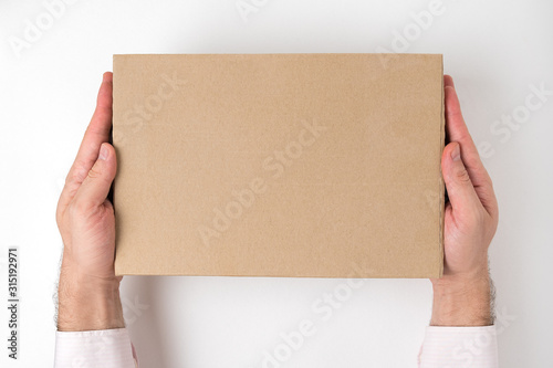 Rectangular cardboard box into men's hands on white background. Delivery service concept. Top view © somemeans