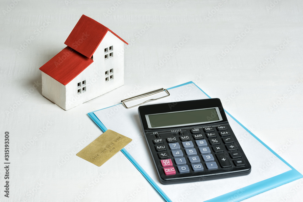 Model of house, credit card and calculator on white background. Buying a home. Concept of mortgage and real estate. Model of house, credit card and calculator on white background. Buying a home. Concept of mortgage and real estate.