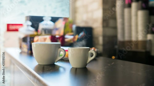 two cups of hot coffee on a bar counter behind frozen winter window 