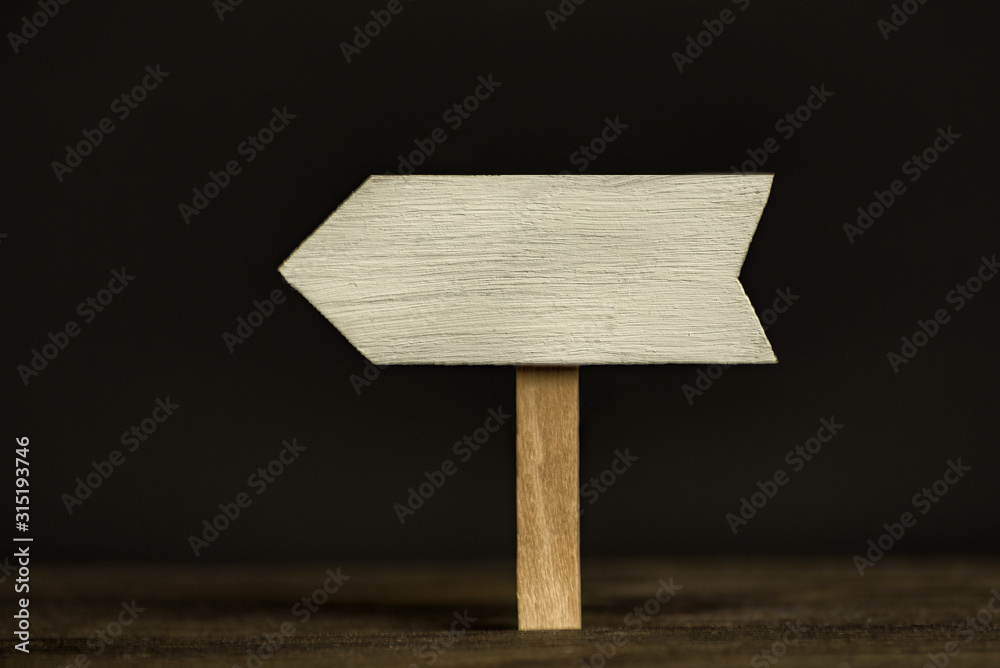 Wooden signpost on black background. Front view, closeup