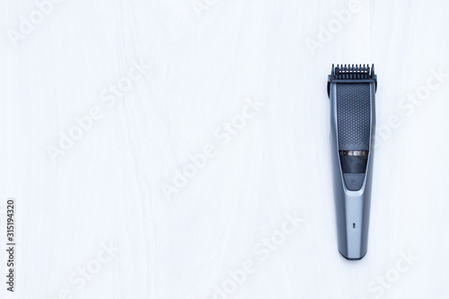 Hair trimmer on white wooden background. Copy space, top view. photo