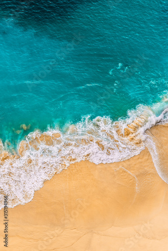 Beautiful sandy beach with turquoise sea, vertical view. Drone view of tropical turquoise ocean beach Nusa penida Bali Indonesia. Lonely sandy beach with beautiful waves. Beaches of Indonesia. © MISHA