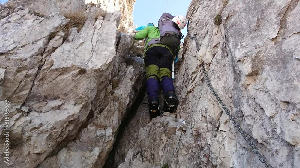 Mountaineer during ascent on an equipped mountain path Mountaineer during ascent on an equipped mountain path