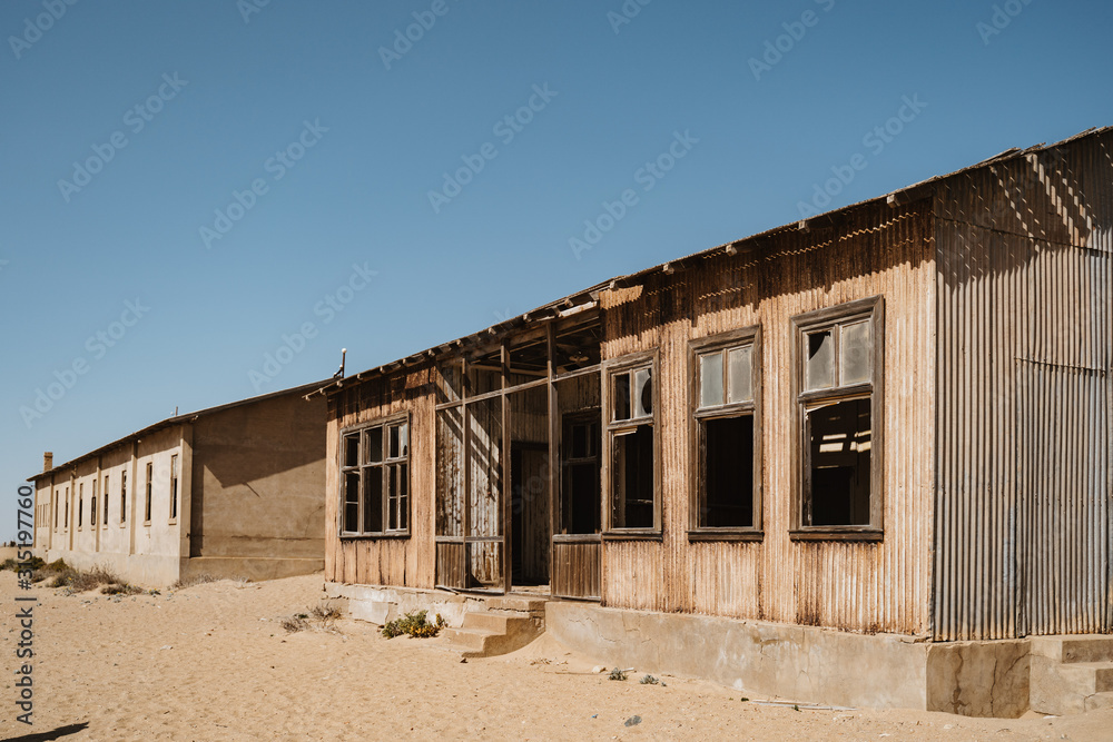 Abandoned buildings left to rot in wild west scenery with desert sand Abandoned buildings left to rot in wild west scenery with desert sand
