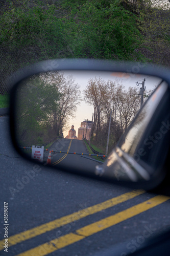 a sunset subtly paints the sky as seen through the rearview mirror of a moving car © Chadd