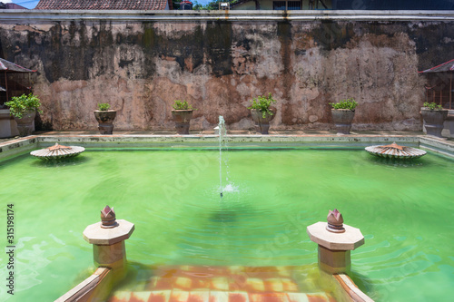 A fountain in an old pool with emerald water. A swimming complex Umbul Passiraman at Taman Sari palace of Yogyakarta, Java. Near Keraton Palace photo