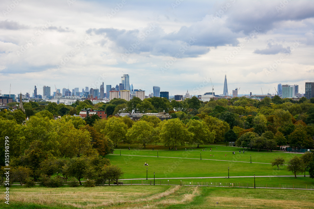 Skyline of the Central London from the Primrose Hill in Regent's Park on a cloudy day with the skyscrapers of City of London and Canary Wharf, the dome of St Paul's Cathedral and the Shard