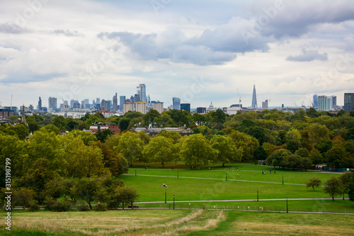 Skyline of the Central London from the Primrose Hill in Regent's Park on a cloudy day with the skyscrapers of City of London and Canary Wharf, the dome of St Paul's Cathedral and the Shard