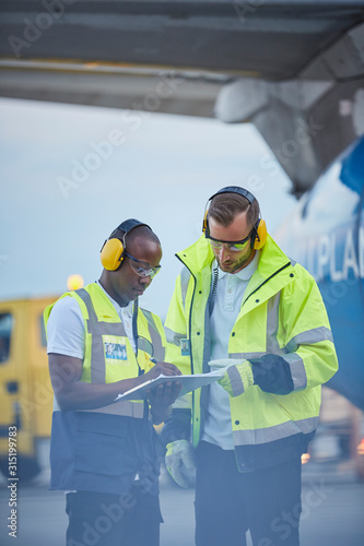 Air traffic controllers with clipboard talking on airport tarmac