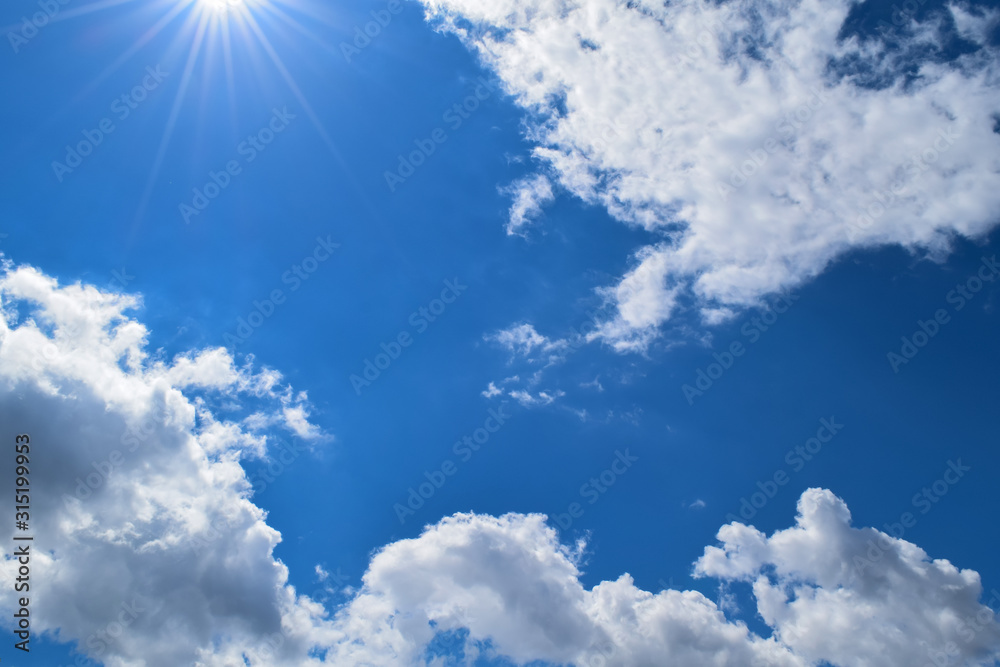 Blue Sky with Bright White Clouds and Sun Flare
