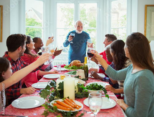 Grandfather making toast with wine at Christmas dinner table