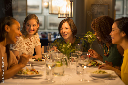 Smiling women friends dining at restaurant table photo