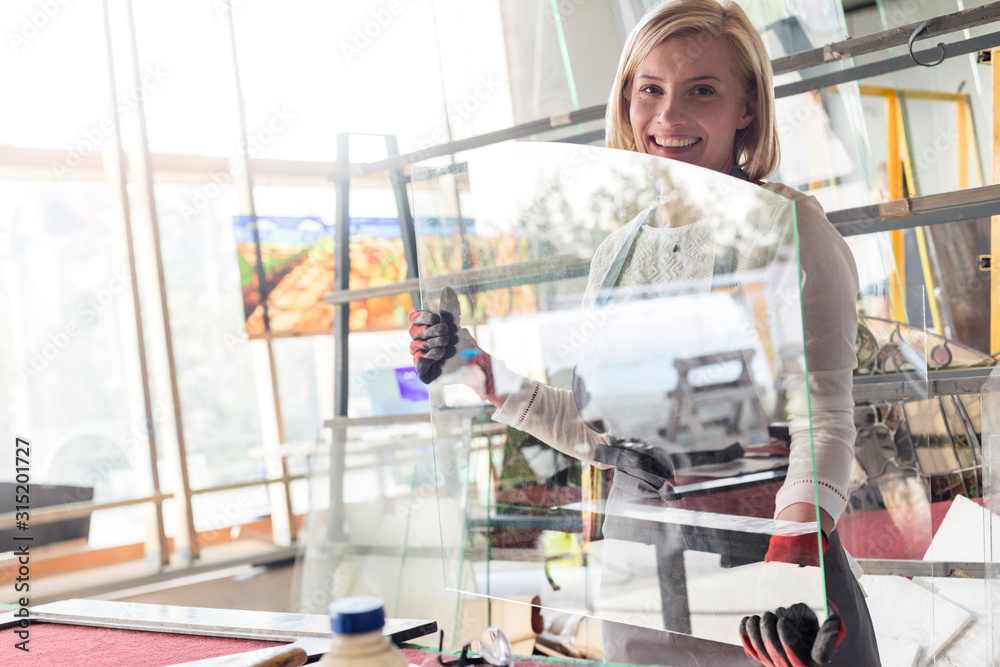 Portrait smiling stained glass artist lifting glass in studio Portrait smiling stained glass artist lifting glass in studio