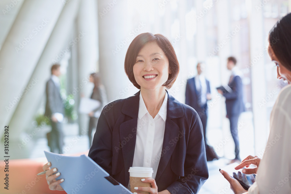 © Tom Merton/Caia Image - Portrait smiling businesswoman drinking coffee reviewing paperwork in office lobby © Tom Merton/Caia Image - Portrait smiling businesswoman drinking coffee reviewing paperwork in office lobby