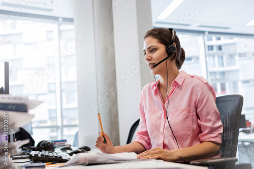 Businesswoman handsfree device talking on telephone at office desk