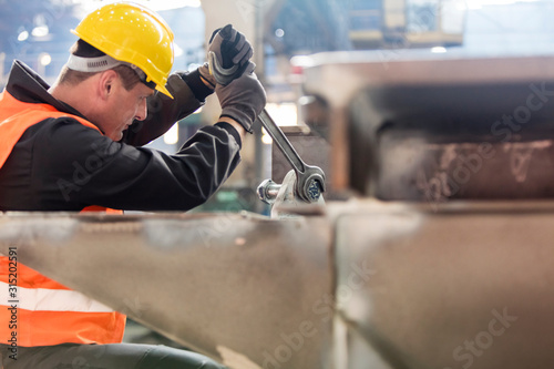 Steel worker using large wrench in factory