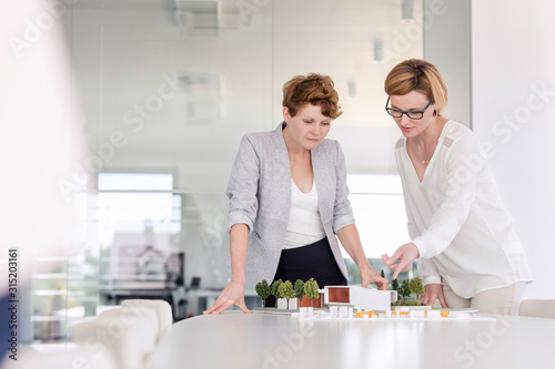 Female architects discussing model in conference room