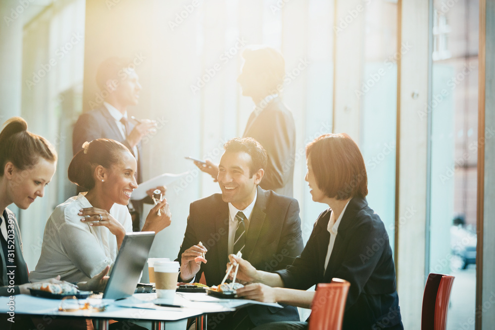 © Tom Merton/Caia Image - Smiling business people eating sushi lunch chopsticks in conference room meeting