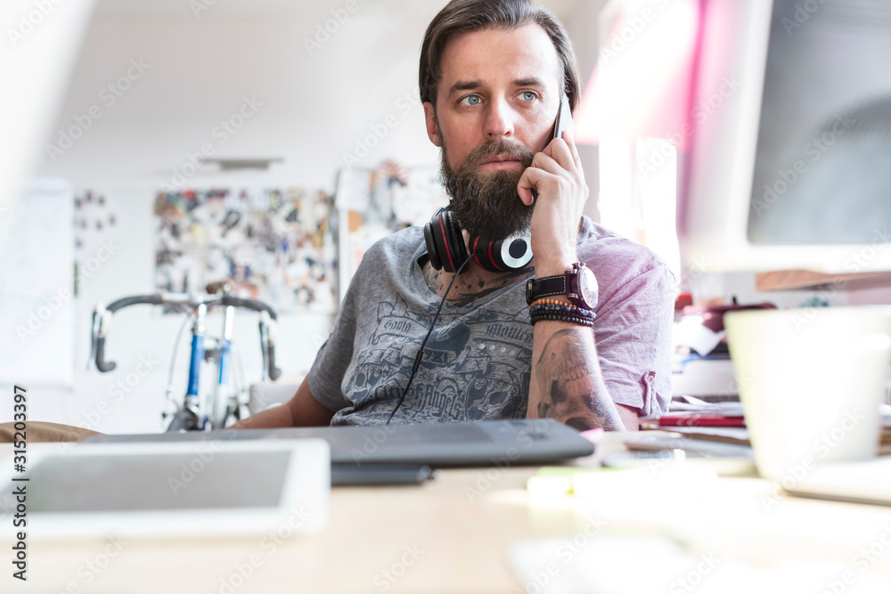 © Rafal Rodzoch/Caia Image - Pensive design professional headphones talking on cell phone at desk © Rafal Rodzoch/Caia Image - Pensive design professional headphones talking on cell phone at desk