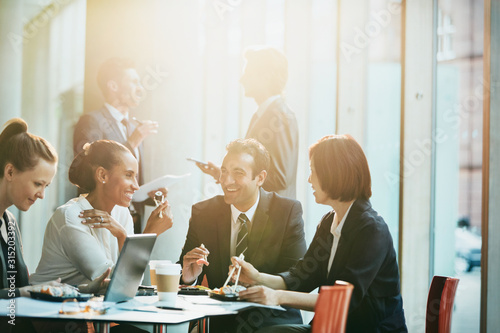 Smiling business people eating sushi lunch chopsticks in conference room meeting
