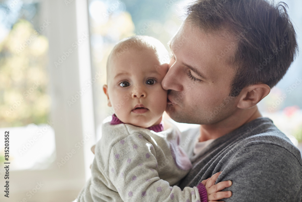 Portrait baby daughter being kisses on cheek by father Portrait baby daughter being kisses on cheek by father