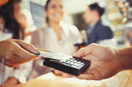Woman credit card paying bartender contactless payment at bar