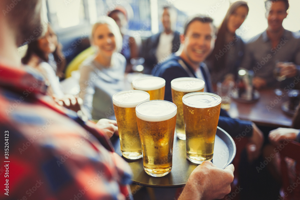 Bartender serving tray of beers to friends in bar Bartender serving tray of beers to friends in bar