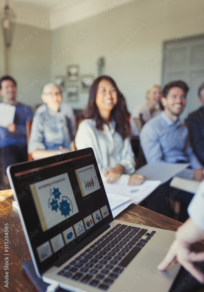 Audience watching businessman at laptop leading conference presentation Audience watching businessman at laptop leading conference presentation