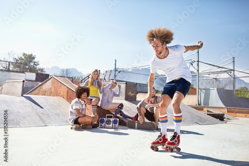 Friends watching man roller skating at sunny skate park photo