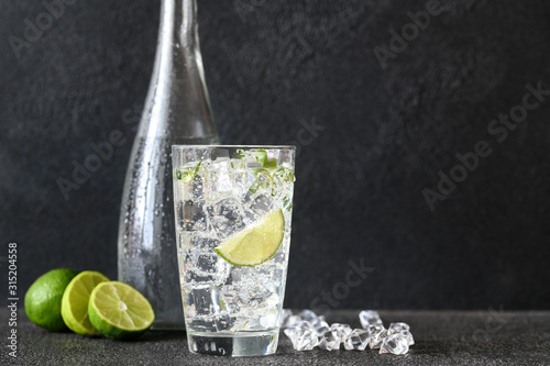 Glass of sparkling water with ice cubes and slice of lime