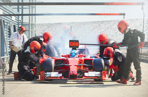 Pit crew working on formula one race car in pit lane photo