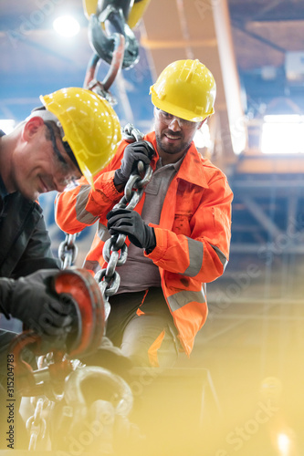 Steel workers with crane hook in factory