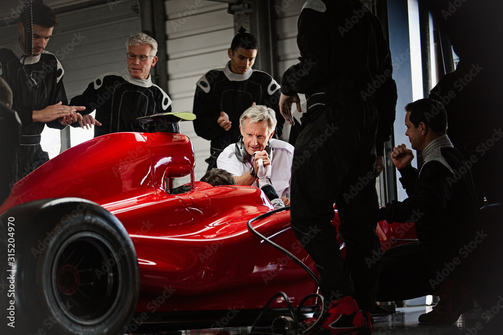 Manager pit crew working on formula one race car in dark repair garage Manager pit crew working on formula one race car in dark repair garage