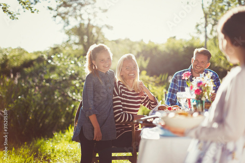 Happy family enjoying lunch at sunny garden party patio table photo