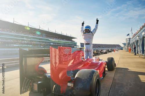 Formula one race car driver cheering on sports track, celebrating victory photo