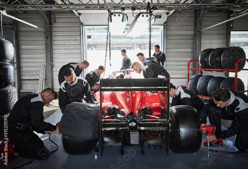 Pit crew working on formula one race car in repair garage photo