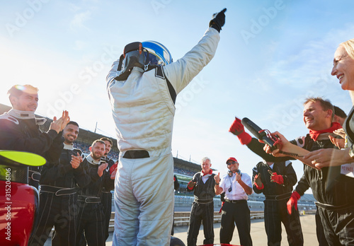 Formula one racing team driver cheering, celebrating victory on sports track photo