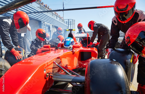 Pit crew replacing tires on formula one race car in pit lane