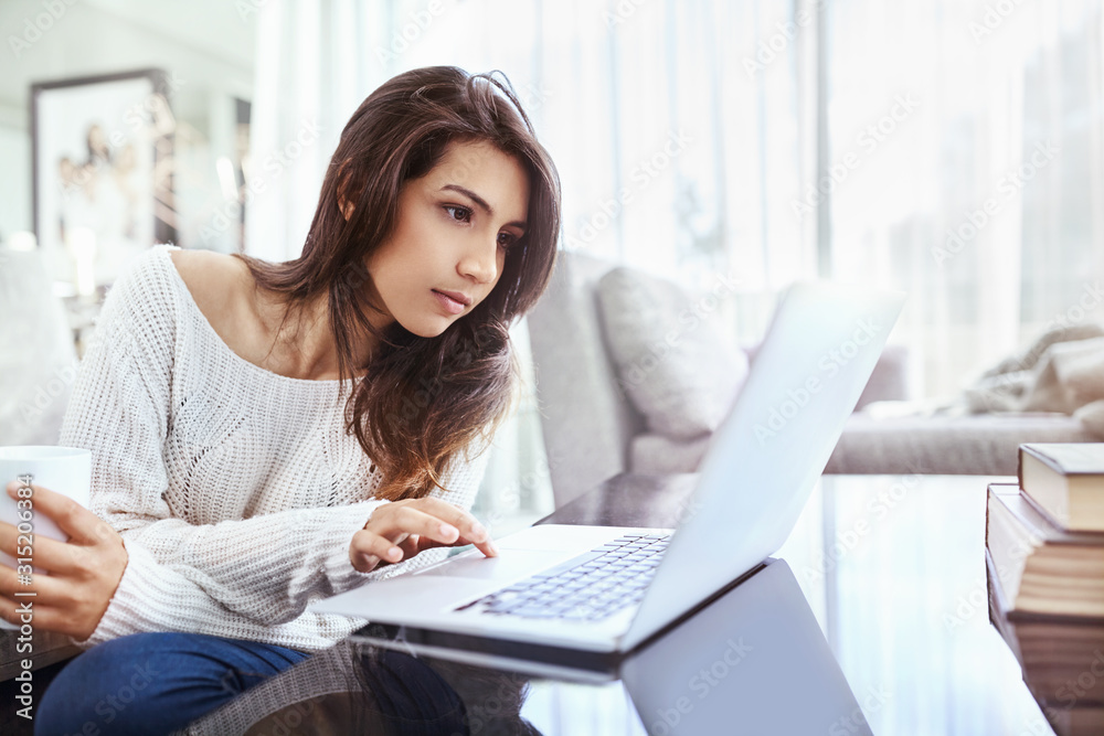Serious woman using laptop at dining table Serious woman using laptop at dining table