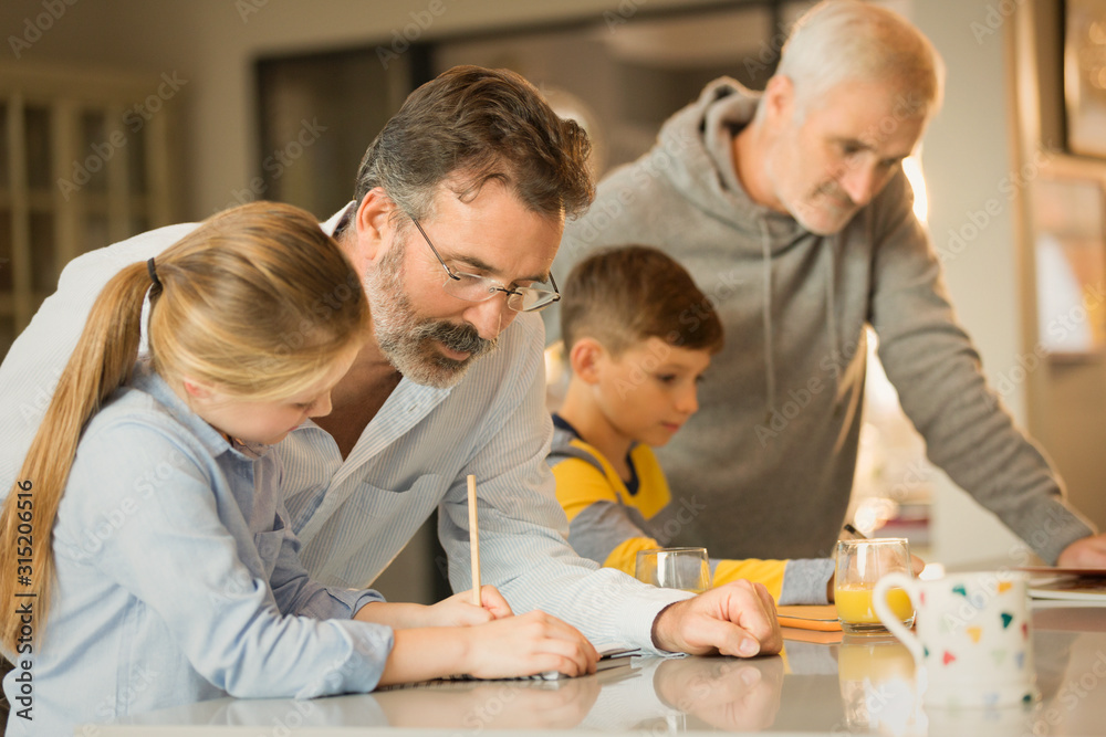 Male gay parents helping children doing homework at counter Male gay parents helping children doing homework at counter
